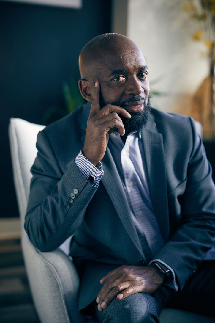 MuRay (Courtney A. Kazembe), seated in a suit